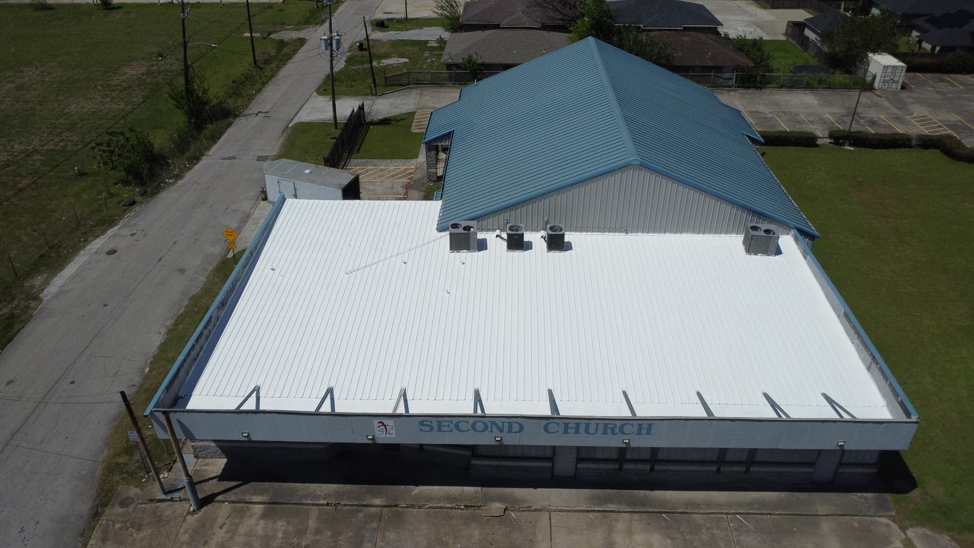Church building with a white reflective roof coating applied over the low-slope metal roof section