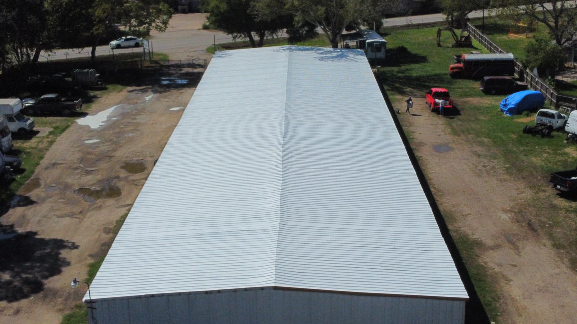 Aerial view of a long metal-roofed commercial building after coating application