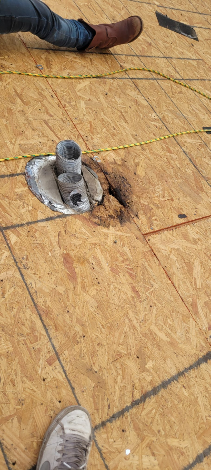 Water-damaged, rotted OSB roof decking exposed around a pipe penetration during a residential leak investigation