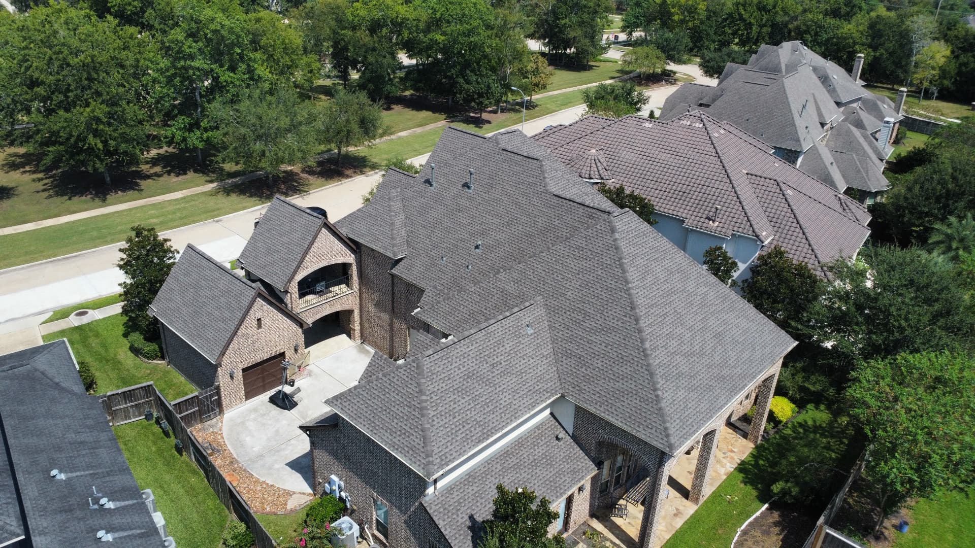 Aerial view of a large multi-gabled Houston-area home with a charcoal architectural shingle roof installed by BD Roofing & Contracting