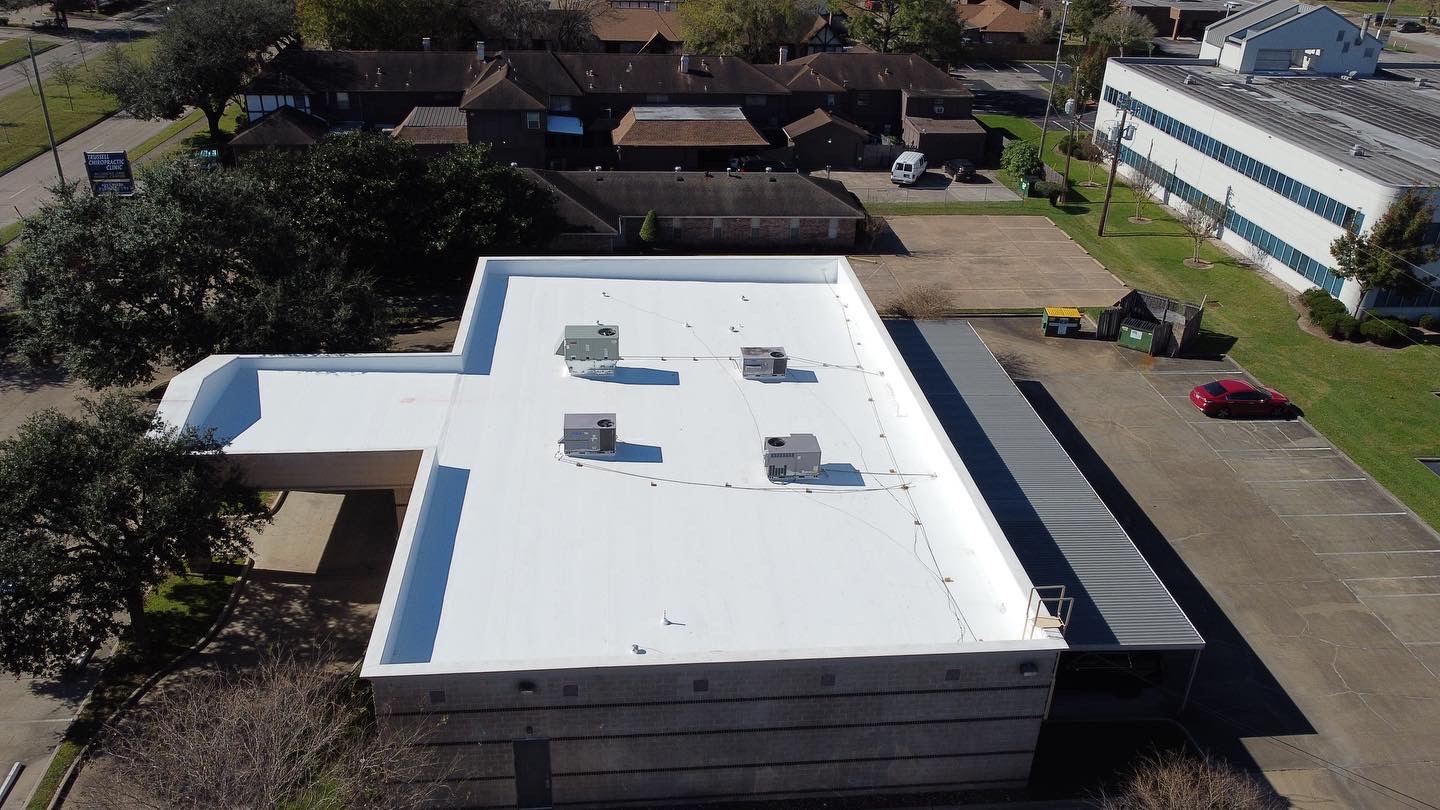 Flat commercial roof with a bright white membrane system and rooftop HVAC units